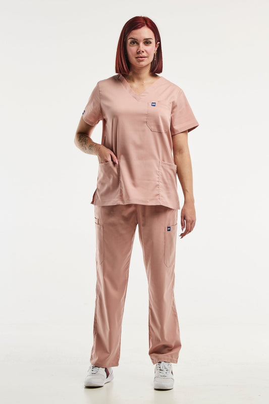 Femme portant la tenue médicale Emma en rose clair, pantalon médical ajusté pour femme