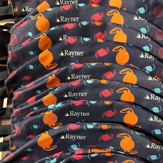 Tissu avec un motif répété de kettlebells orange, rouge et bleu et le texte ’Rayner’ sur un fond noir.