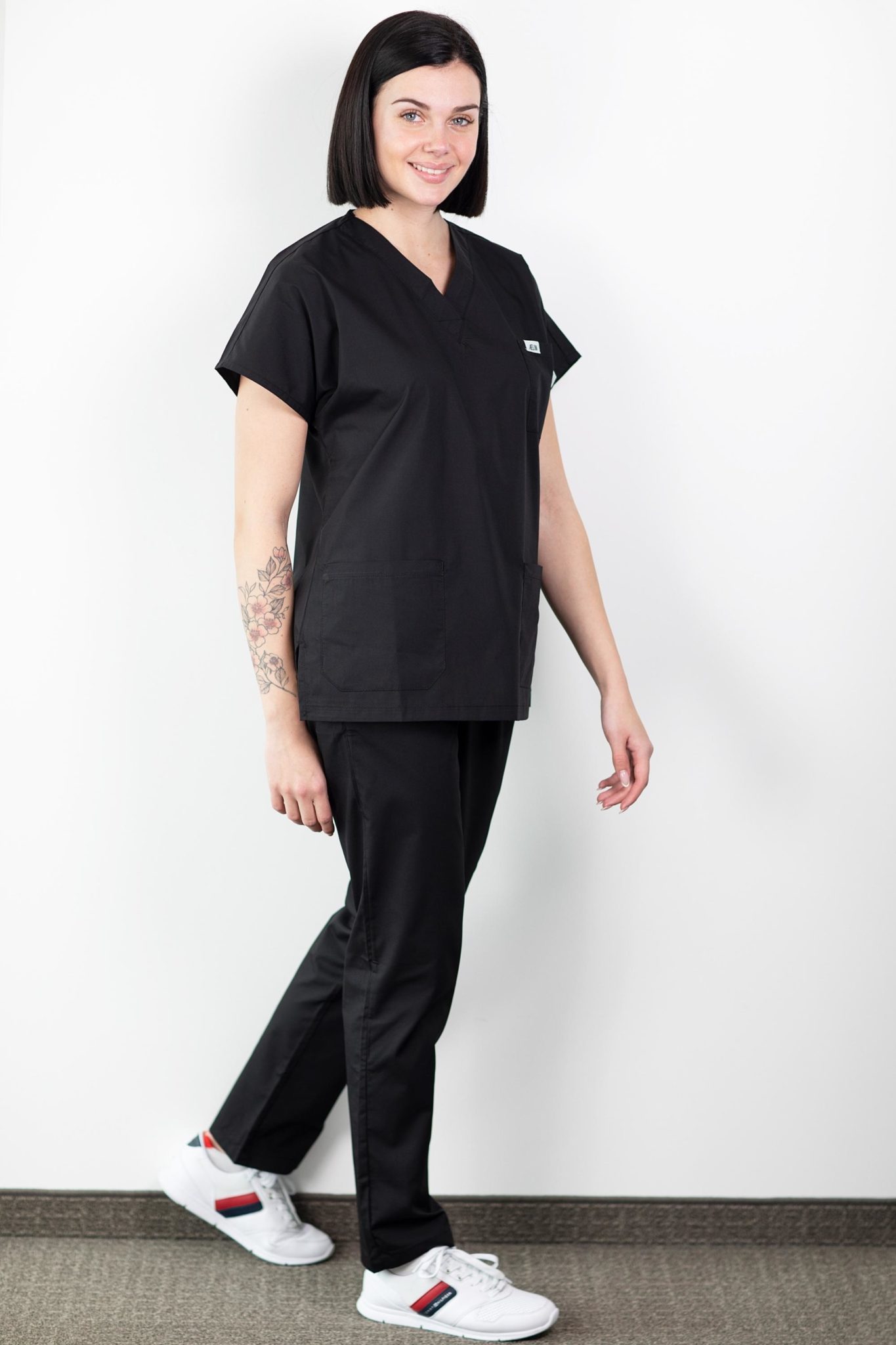 Healthcare worker en tunique médicale noire et chaussures blanches dans un uniforme