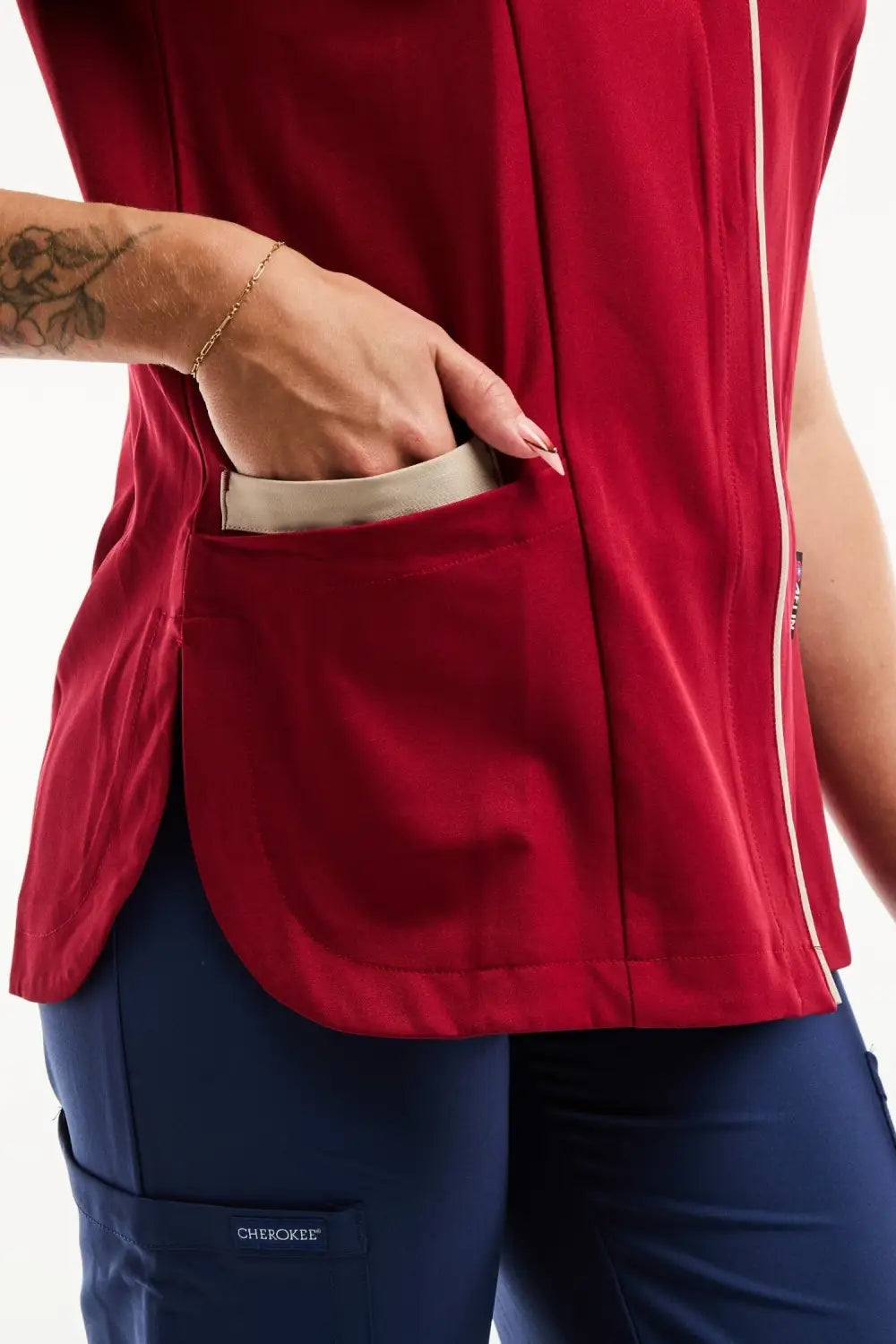 Blouse médicale Serena bordeaux avec gilet rouge, pantalon bleu marine et bracelet doré