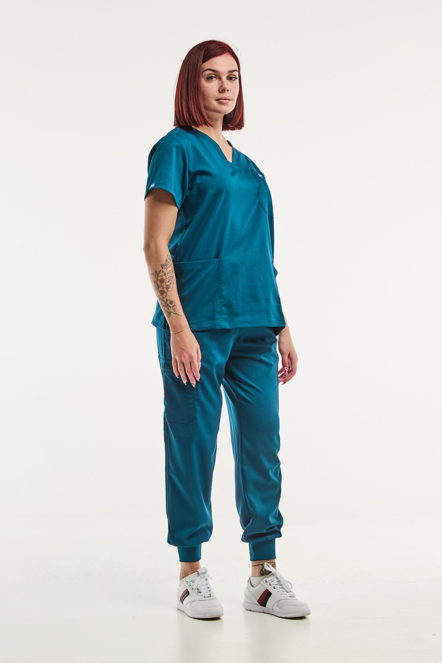 Veste de scrub turquoise avec sneakers blanches pour femme en tenue médicale