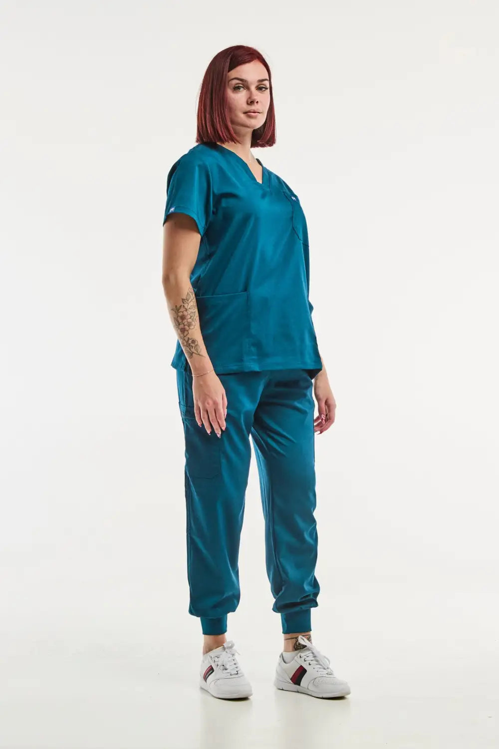 Veste de scrub turquoise avec sneakers blanches pour femme en tenue médicale