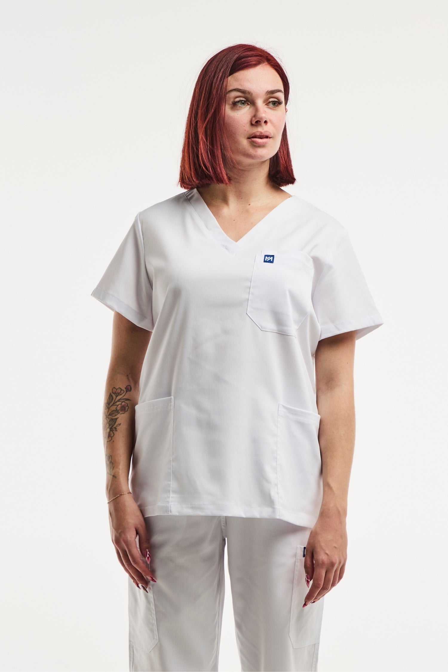 Tunique médicale col V blanche pour femme avec poches, portée par une femme aux cheveux roux