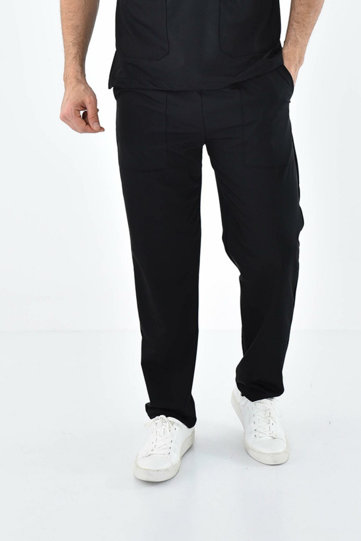 Homme en costume noir avec chaussures blanches portant un pantalon médical confortable