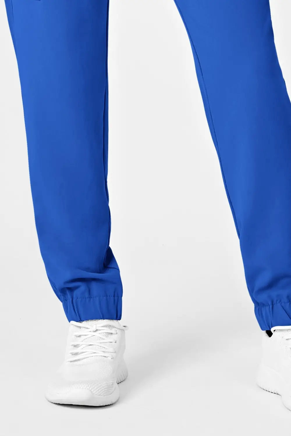 Femme en pantalon médical bleu royal coupe moderne avec poches cargo, chaussures blanches