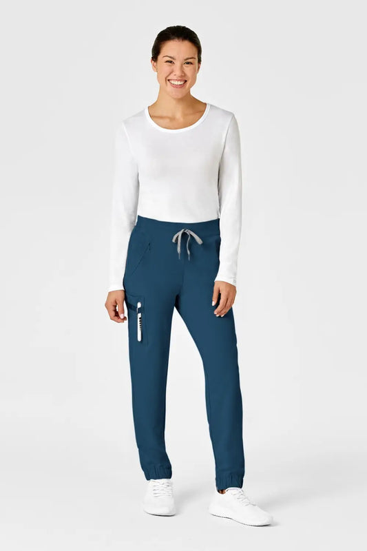 Une femme en pantalon médical bleu turquoise avec coupe moderne et poches classiques