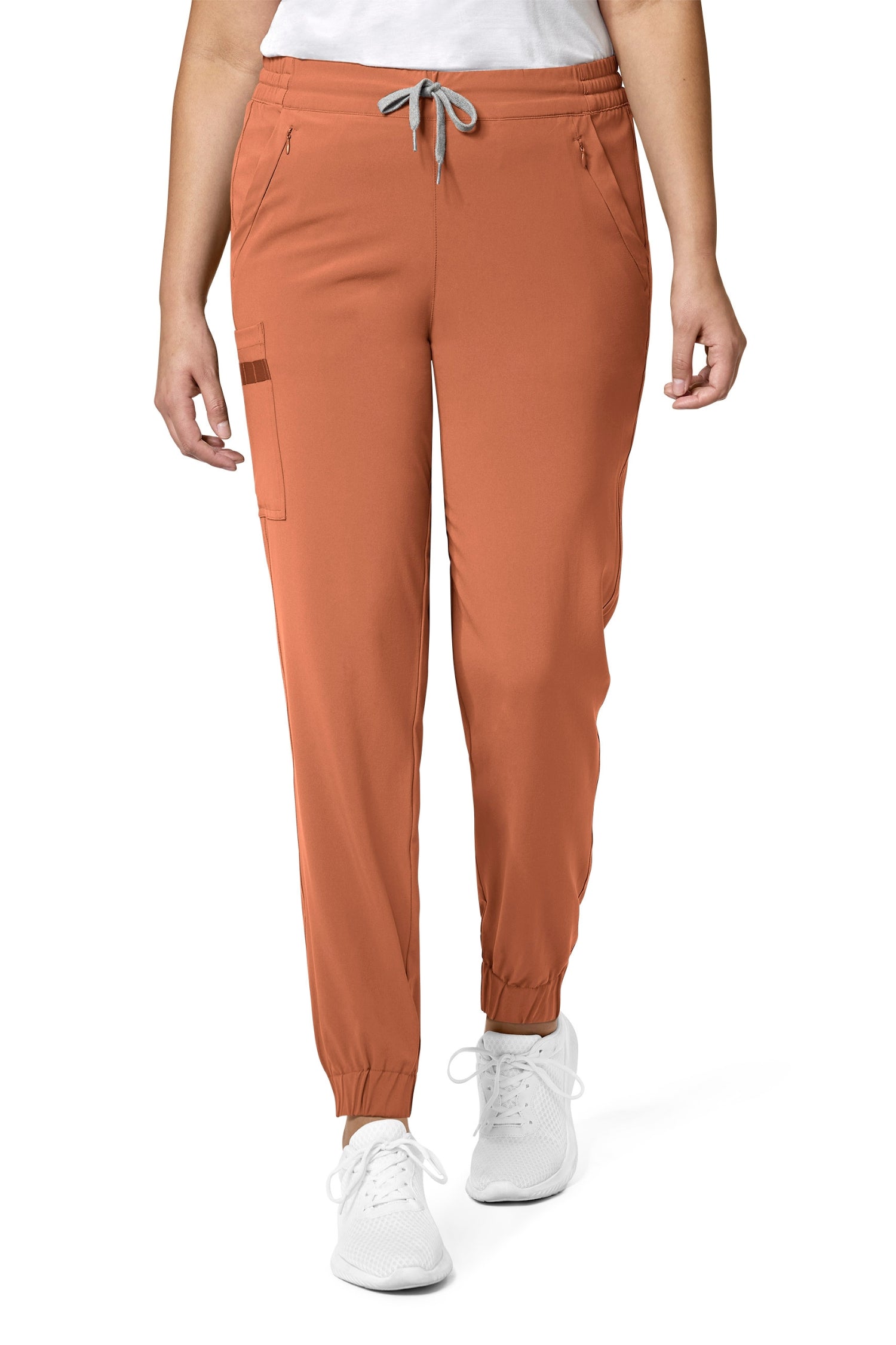 Femme en pantalon marron coupe moderne et poches classiques, portant des sneakers blanches