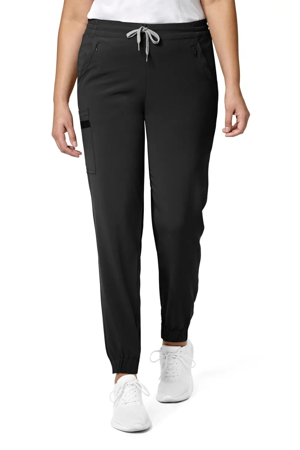 Femme en pantalon médical noir coupe moderne avec poches classiques et sneakers blanches