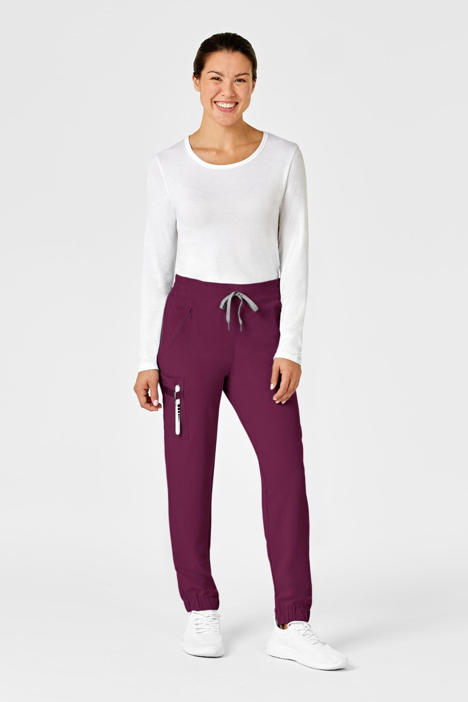 Femme en tenue médicale bordeaux avec poches à fermeture et tissu polyester spandex