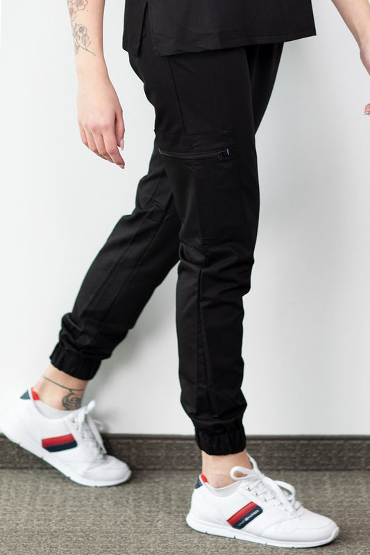 Homme en chemise noire et baskets blanches portant un pantalon médical Slimfit NEW noir