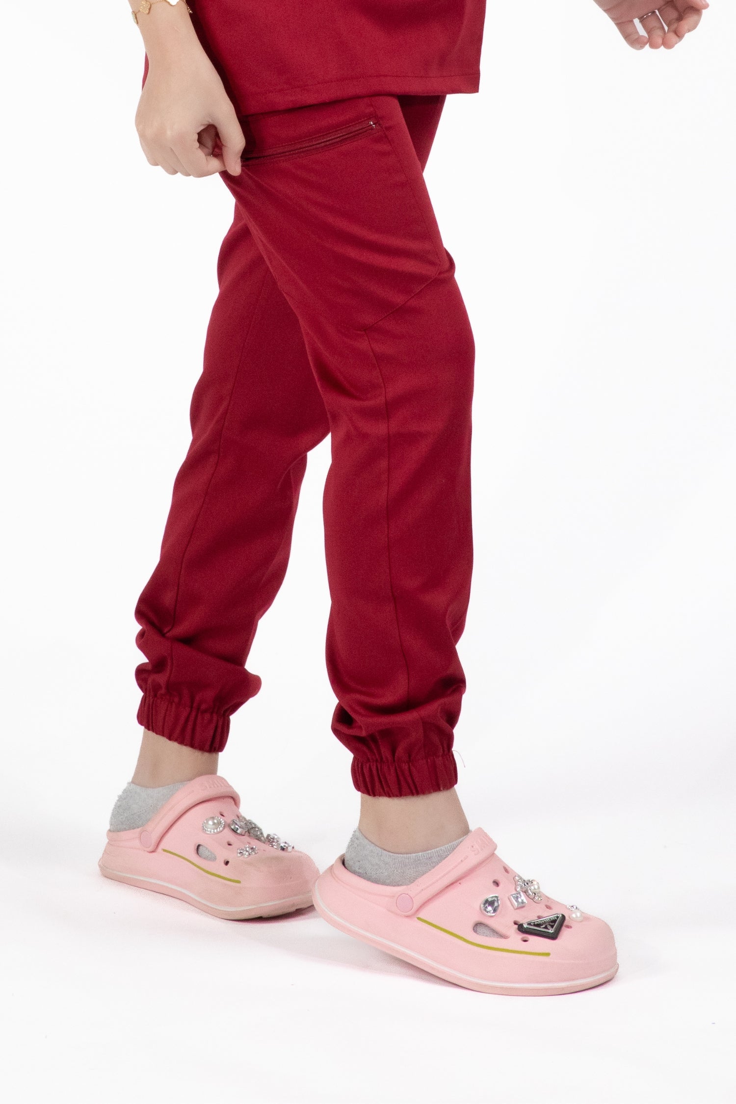 Petite fille en sweatshirt rouge et chaussures roses portant le pantalon médical Rouge Bordeaux