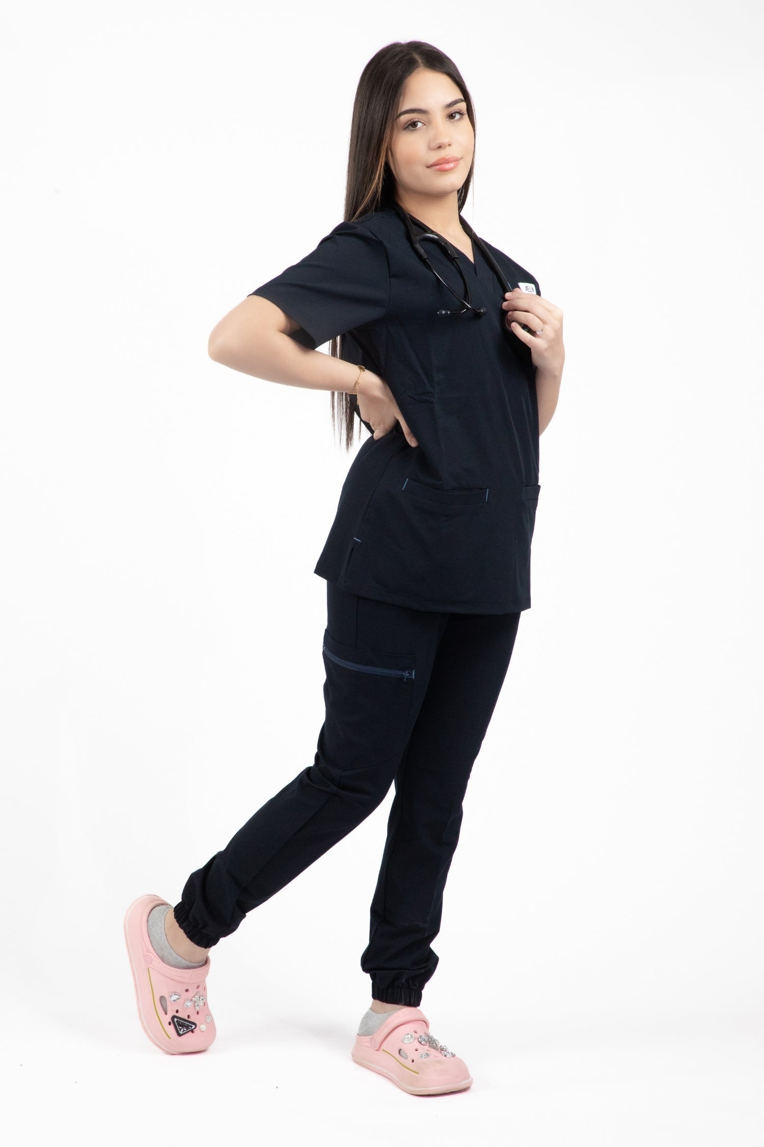 Une femme en uniforme médical noir portant une blouse et un pantalon Slimfit Tenue médicale